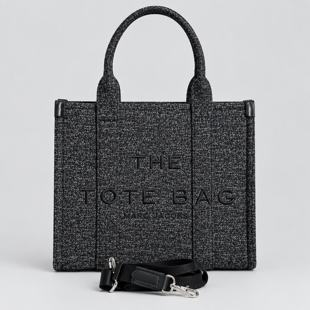 A dark gray woven tote bag with black handles and a matching black detachable shoulder strap, displayed against a light gray brick-patterned wall.